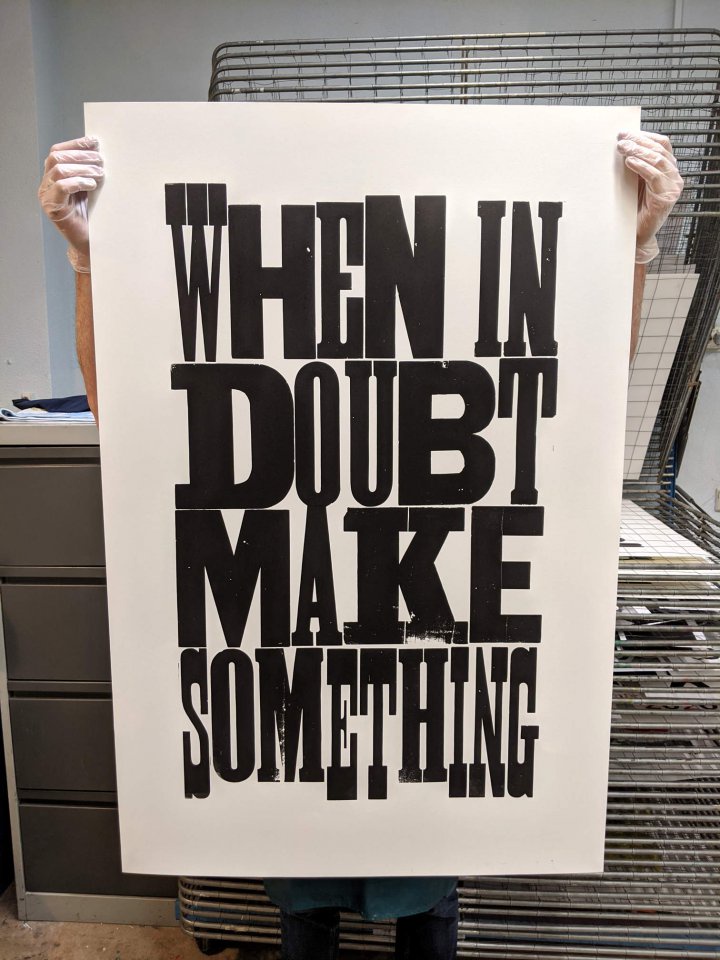 A large letterpress poster with the text 'When in doubt, make something' printed in black with mixed wood type on white paper.