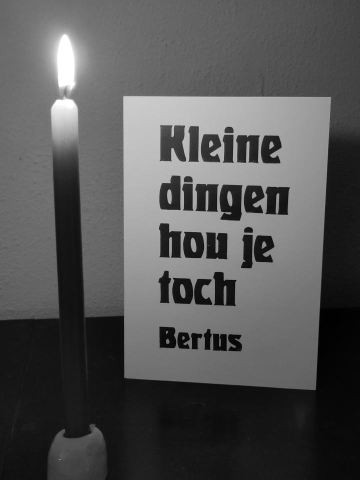 A card standing next to a small lighted candle.