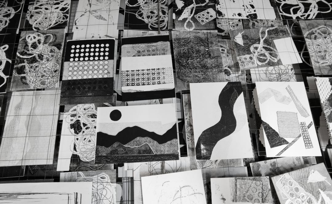 Many A5 sized prints in black and white lying in a drying rack.