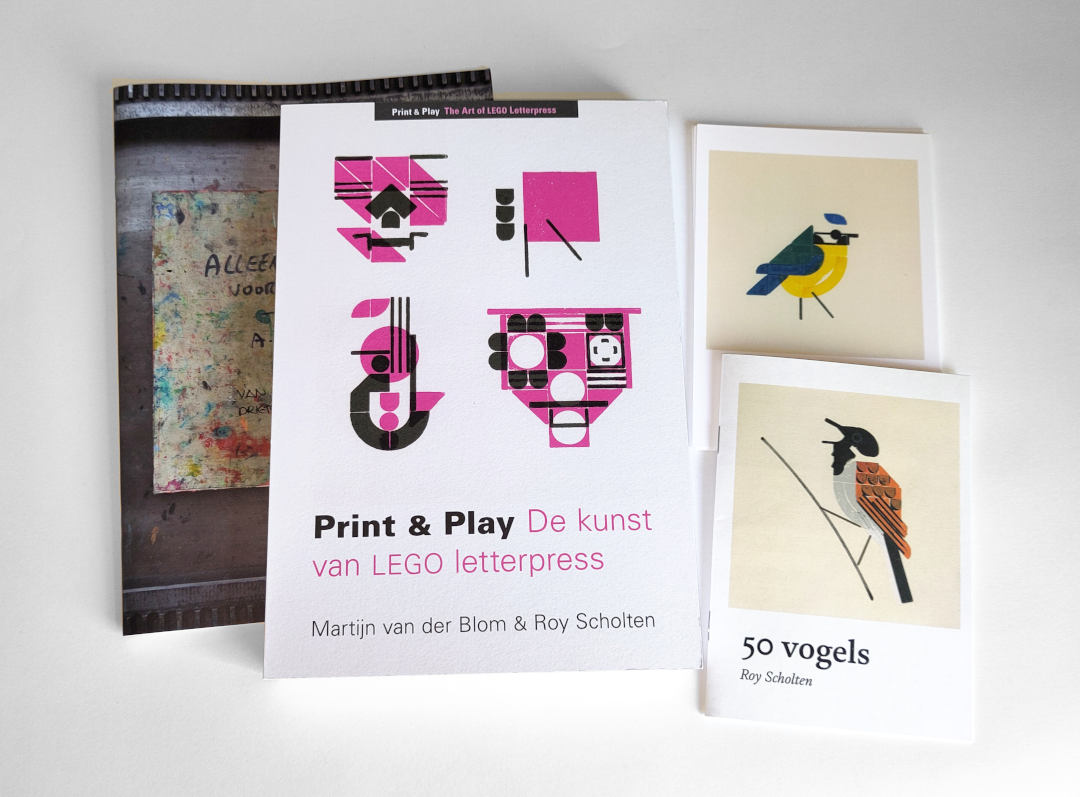 Een boek, magazine en ansichtkaarten op witte achtergrond in matige belichting gefotografeerd.