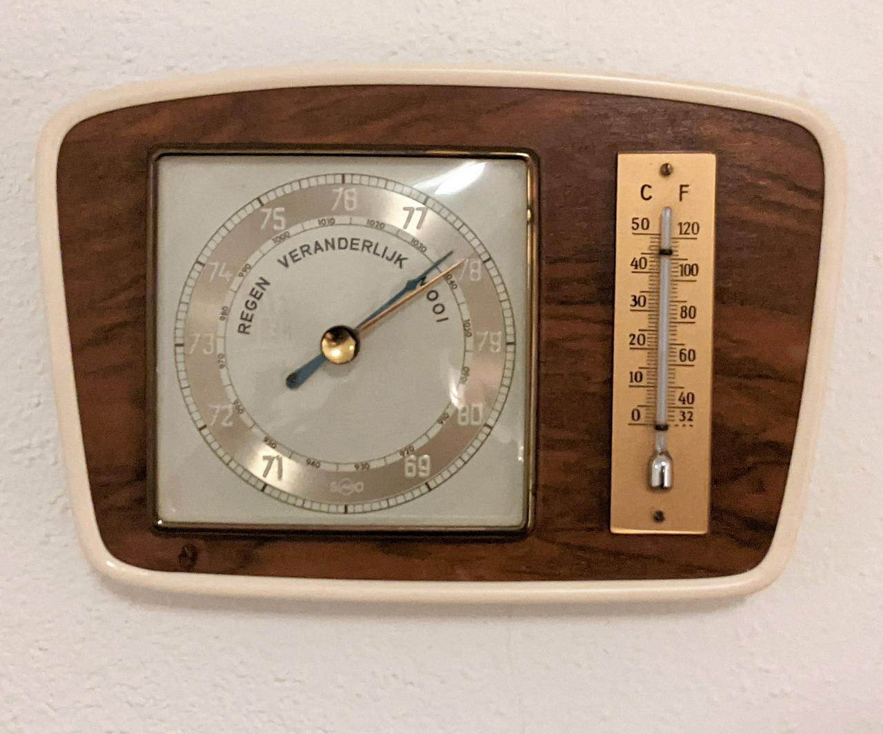 Foto van een ouderwetse barometer. De wijzers staan op 'mooi'.